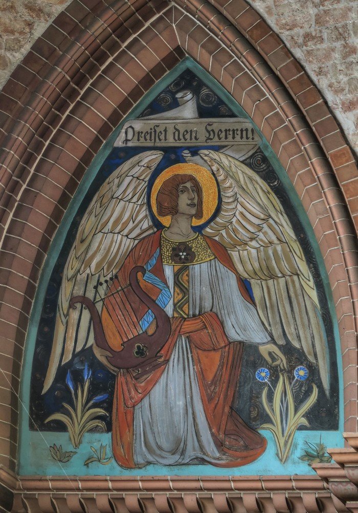 Foto mit Wandmalerei: Ein Engel mit Text "Preiset den Herrn!"