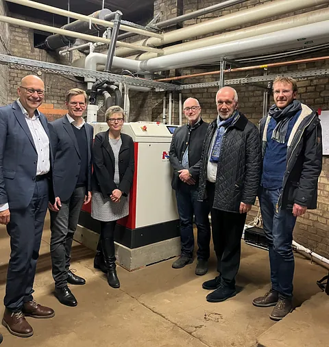 Projektbeteiligte stehen im Heizungskeller der Apostel-Paulus-Kirche vor der neuen Heizung - von links: Superintendent Michael Raddatz, Gunnar Wilhelm (GASAG), Pfarrerin Martina Steffen-Eliş, Dr. Stefan Irmisch (GASAG), Reinhard Müller (GASAG), Leander Giese (GASAG)