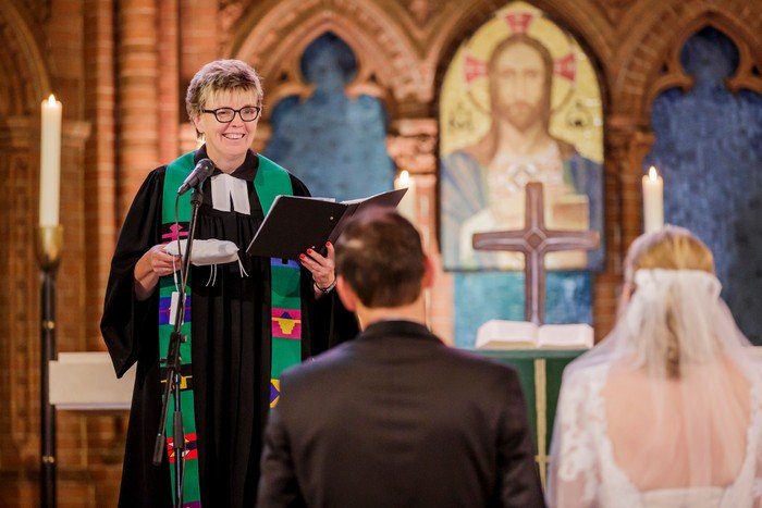 Foto einer Hochzeit in der Apostel-Paulus-Kirche mit Pfarrerin Steffen-Eliş und einem knieenden Brautpaar