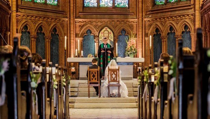 Foto mit Brautpaar und Pfarrerin Steffen-Elis im Altarraum der Apostel-Paulus-Kirche
