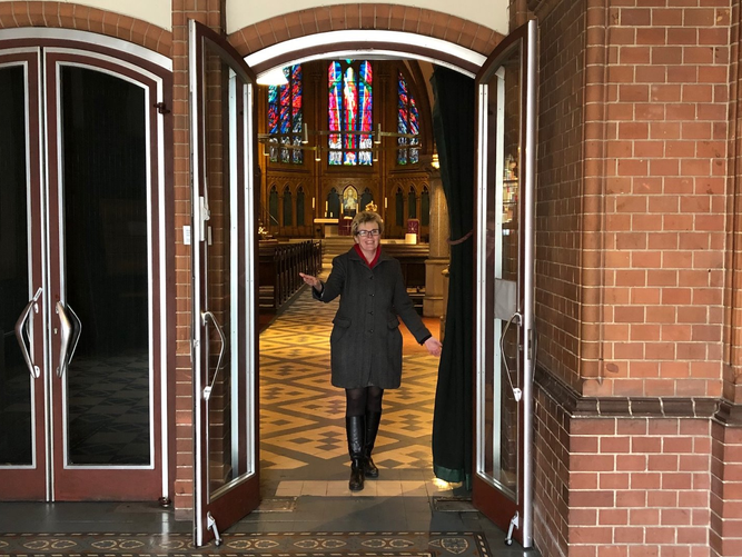 Pfarrerin Steffen-Elis steht in der geöffneten Tür der Apostel-Paulus-Kirche